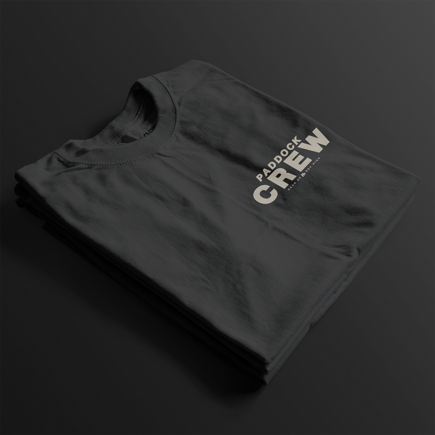 Paddock Crew Automotive T-Shirt – folded front view of dark grey Paddock Crew graphic tee featuring bold "Paddock Crew" text and "Gear Up, Rev High" tagline. Perfect gift for motorsport and car culture enthusiasts.